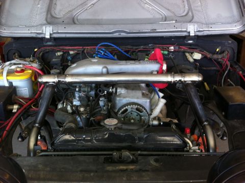 1987 Suzuki Samurai - Engine bay of a 1987 Suzuki Samurai, showing the engine, battery, and various hoses and wires.
