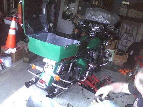 2003 Ford Crown Victoria - A green motorcycle is parked in a garage, a large, open green storage box mounted on the rear.