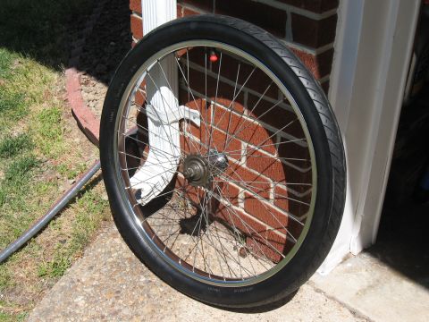 1994 Ford Bronco - A bicycle wheel with a black tire and silver spokes is propped against a brick wall.