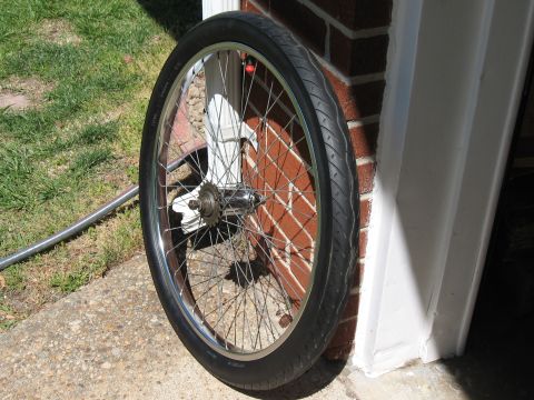 1994 Ford Bronco - A bicycle wheel with a silver rim and black tire rests against a brick wall and white trim.
