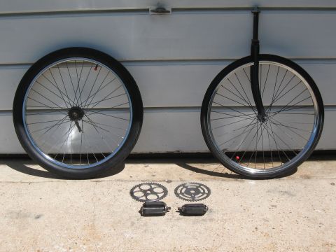 1994 Ford Bronco - A collection of bicycle parts, including two wheels, chainrings, and pedals, are displayed against a garage door.