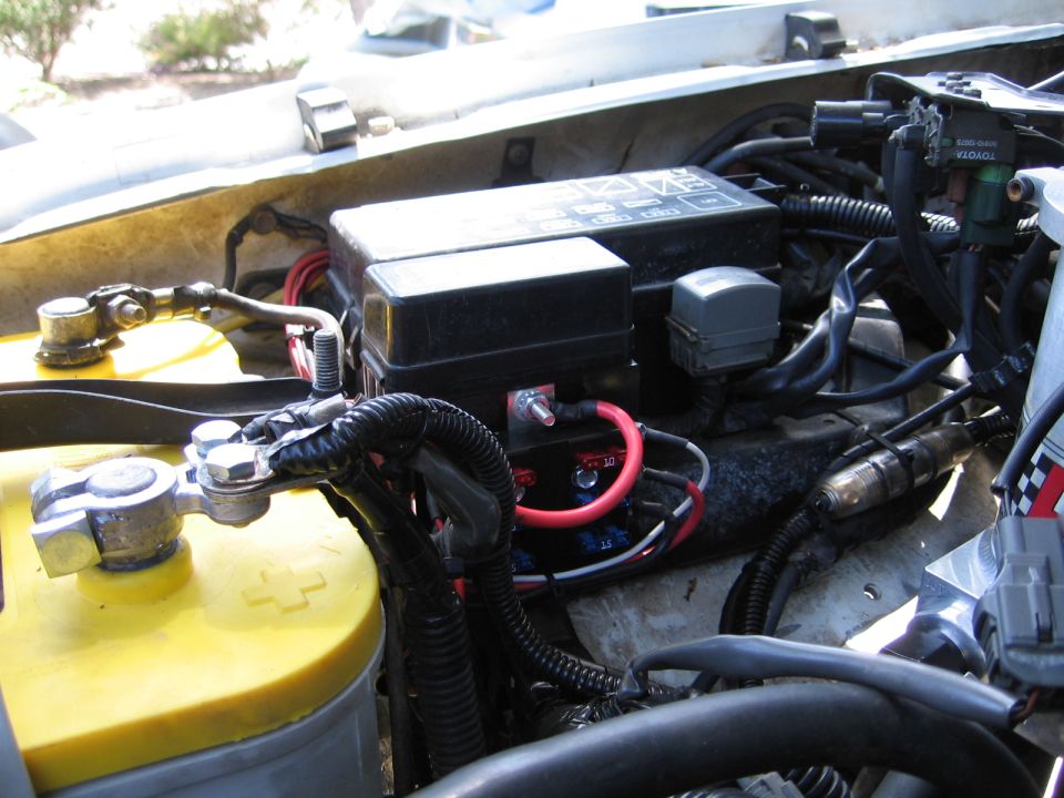 Engine bay with dual batteries, fuse boxes, and wiring. Text 'TOYOTA' visible
