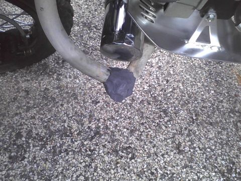 2003 Ford Crown Victoria - A motorcycle's exhaust pipe shows a repair with dark putty at the connection point.