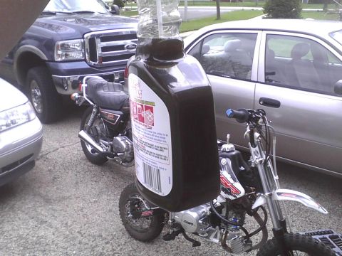 2003 Ford Crown Victoria - A creative modification involves attaching a motor oil bottle to a dirt bike, with other vehicles visible.