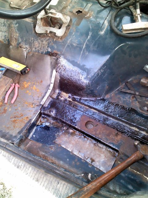 1987 Jeep Comanche - The floor pan of a 1987 Jeep Comanche shows significant rust repair with new metal plates and tools nearby.