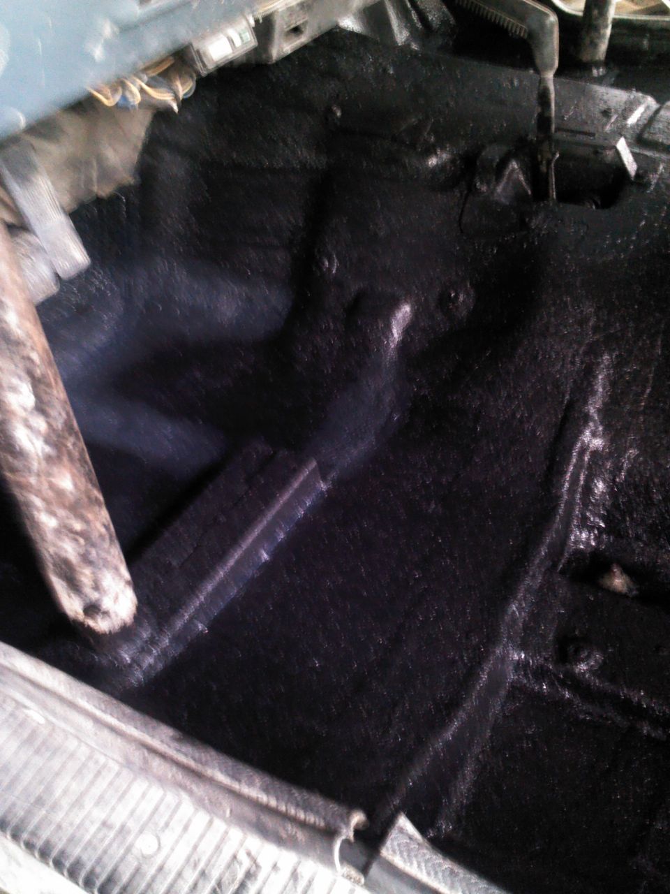 Black painted vehicle floor pan with some metal bracing visible