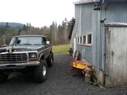 1979 Ford Bronco - A lifted 1978 Ford Bronco is parked on a gravel driveway next to a rustic barn with trees in the background.