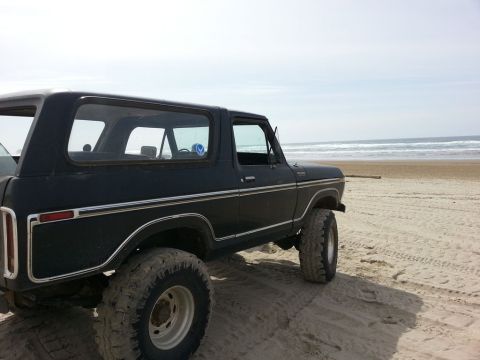 1979 Ford Bronco - This black 1979 Ford Bronco is parked on a sandy beach with the ocean in the background.