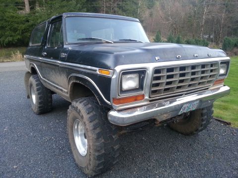 1979 Ford Bronco - This lifted black Ford Bronco is shown from the front quarter angle, equipped with large off-road tires.