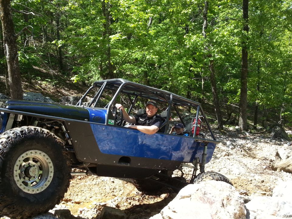 Blue off-road buggy with a roll cage and large tires navigating rocky terrain