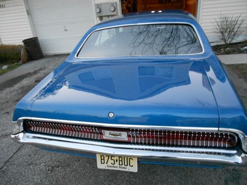 1968 Mercury Cougar - Blue 1968 Mercury Cougar parked in front of a garage, showing its distinctive rear grille and taillights.