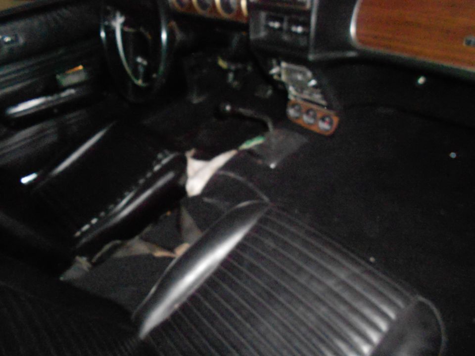 Car interior showing black seats, dashboard, and steering wheel. Some items are on the floor