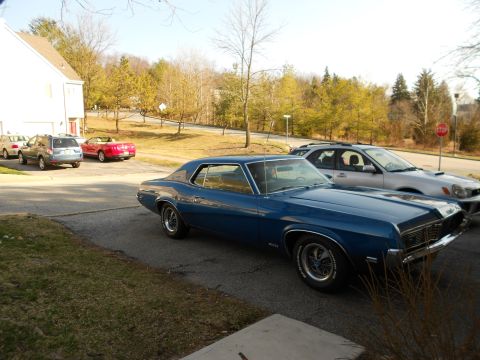 1968 Mercury Cougar - A blue 1968 Mercury Cougar is parked in a driveway with other cars visible in the background.
