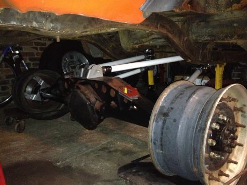 1994 Ford Bronco - The rear axle and suspension of a vehicle are visible, along with spare wheels and a bicycle.