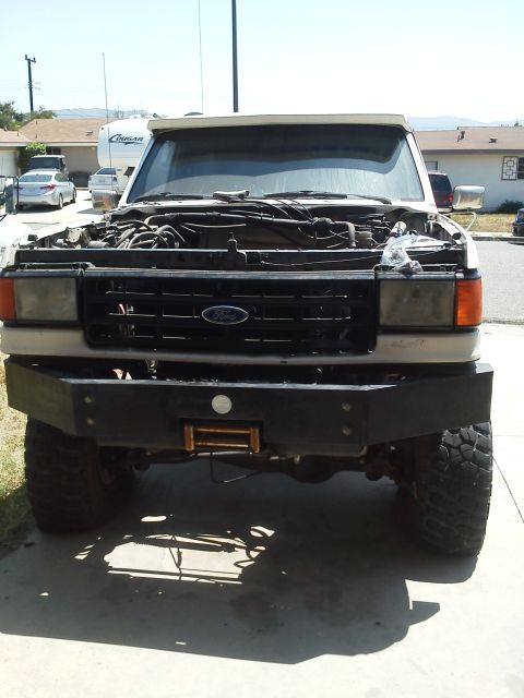 1988 Ford Bronco - Front view of a Ford F-Series truck with its hood open, revealing the engine bay and an aftermarket bumper.