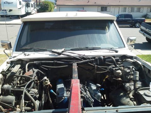 1988 Ford Bronco - The engine bay of a white SUV, with the hood open and engine components visible.