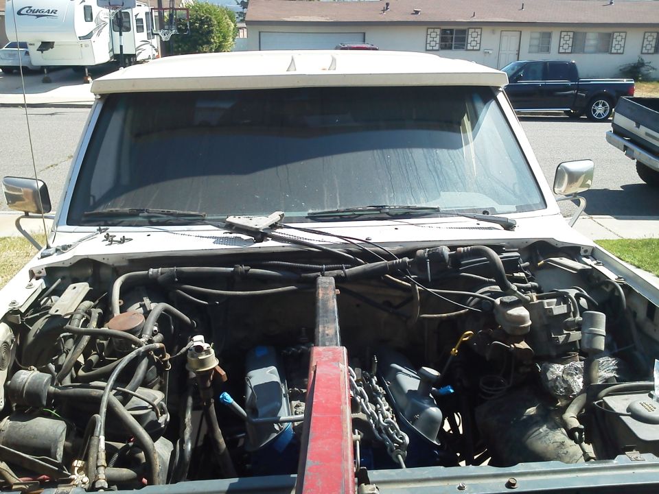White SUV engine bay with engine hoist and chain, showing V8 engine components