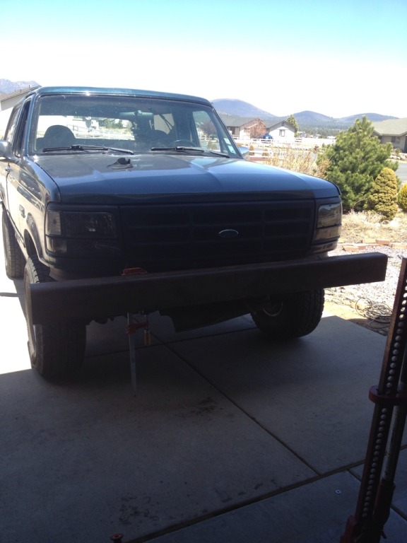 Dark green Ford Bronco with a custom wooden bumper and aftermarket headlights