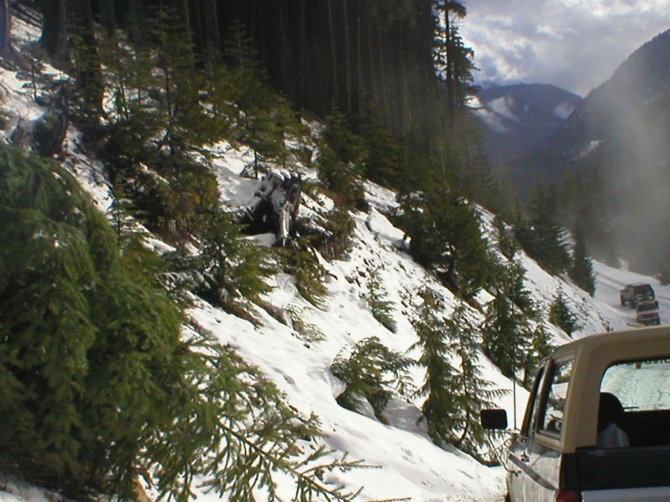 Tan SUV rear view on a snowy mountain road with other SUVs ahead