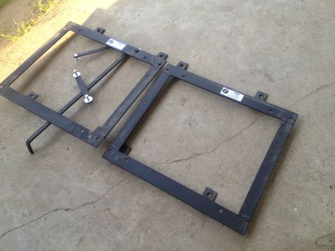 2000 Jeep Wrangler - Two metal seat brackets, likely for a Jeep, are shown on a concrete surface. Labels on the brackets are partially visible.