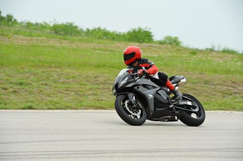 2001 Kawasaki KZ1000-A1 - A rider in full gear navigates a turn on a black sport motorcycle during a track day.