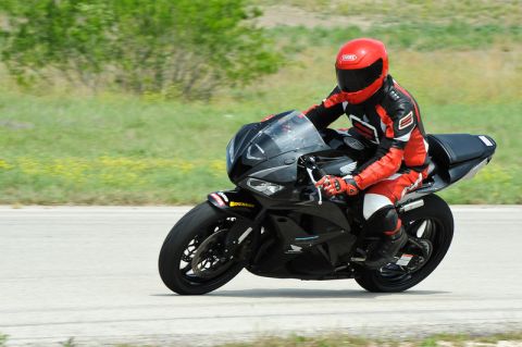 2001 Kawasaki KZ1000-A1 - A rider in full racing gear navigates a turn on a black sport motorcycle.