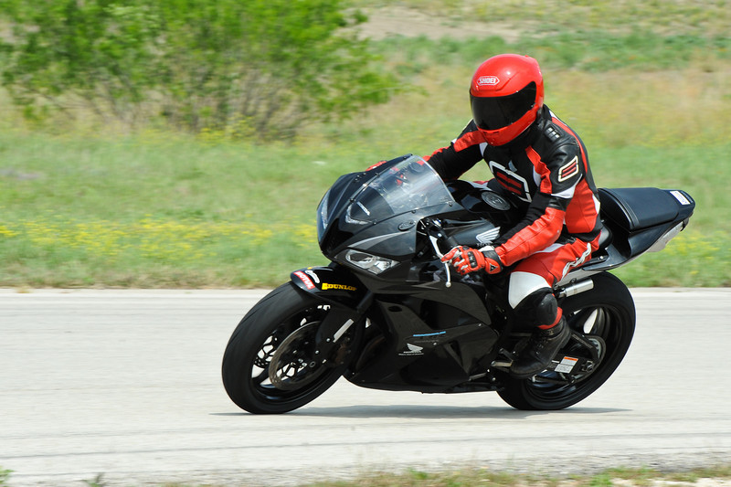 Black motorcycle with rider in red and black gear on a track