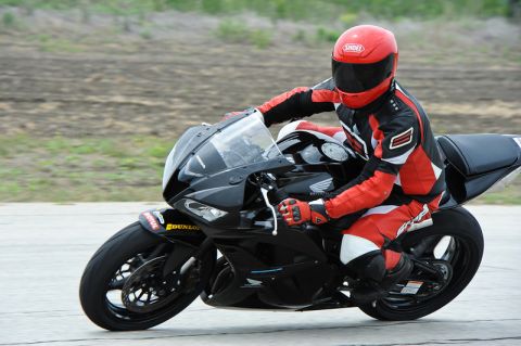 2001 Kawasaki KZ1000-A1 - Rider in full racing suit on a black motorcycle on a paved track.