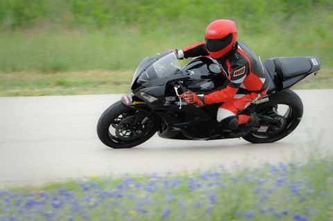 2001 Kawasaki KZ1000-A1 - Rider in full gear on a black sportbike navigates a track.