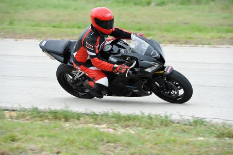 2001 Kawasaki KZ1000-A1 - A motorcycle rider wearing a red helmet and racing suit navigates a turn on a track.