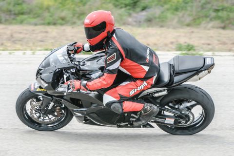 2001 Kawasaki KZ1000-A1 - A rider in full gear maneuvers a black sport motorcycle on a paved surface.