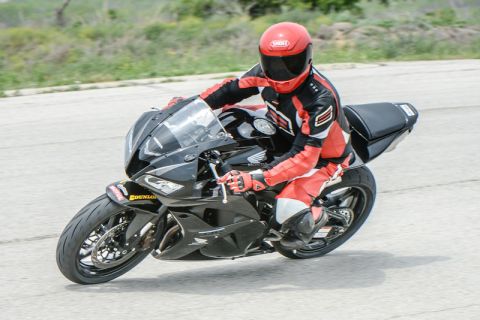 2001 Kawasaki KZ1000-A1 - A motorcycle rider in full gear leans into a turn on a black sportbike with a visible Honda logo.