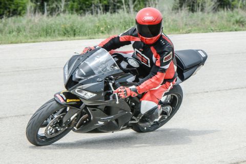 2001 Kawasaki KZ1000-A1 - A rider in full gear maneuvers a black motorcycle on a paved surface.