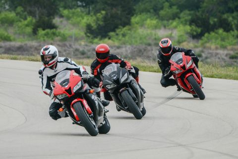 2001 Kawasaki KZ1000-A1 - Riders lean into a turn on a race track with multiple sport motorcycles.