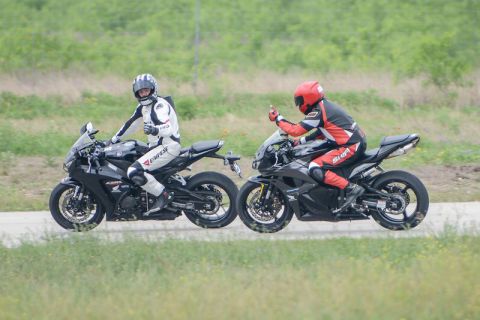 2001 Kawasaki KZ1000-A1 - Two sport motorcycles and their riders are seen on a road with a grassy embankment.