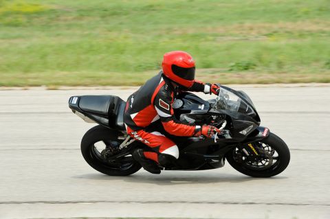 2001 Kawasaki KZ1000-A1 - A rider in a red and black suit on a black motorcycle on a track. The Supermotors.net logo is visible in the lower right corner.