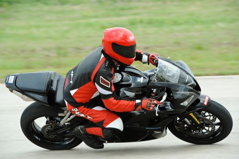 2001 Kawasaki KZ1000-A1 - A motorcycle rider in full racing gear takes a corner on a track.