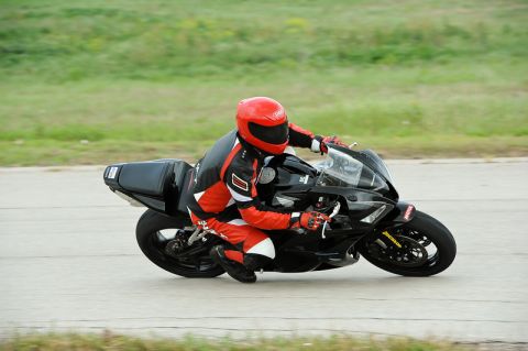 2001 Kawasaki KZ1000-A1 - A rider in full gear maneuvers a black sport motorcycle on a paved track.