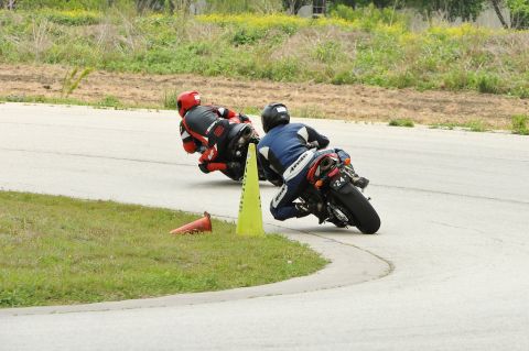 2001 Kawasaki KZ1000-A1 - Two motorcycles lean into a turn on a race track, with a yellow cone marking the apex.