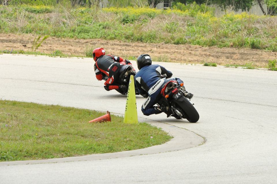 Two motorcycles racing on a track, one in blue and white, the other in red and black