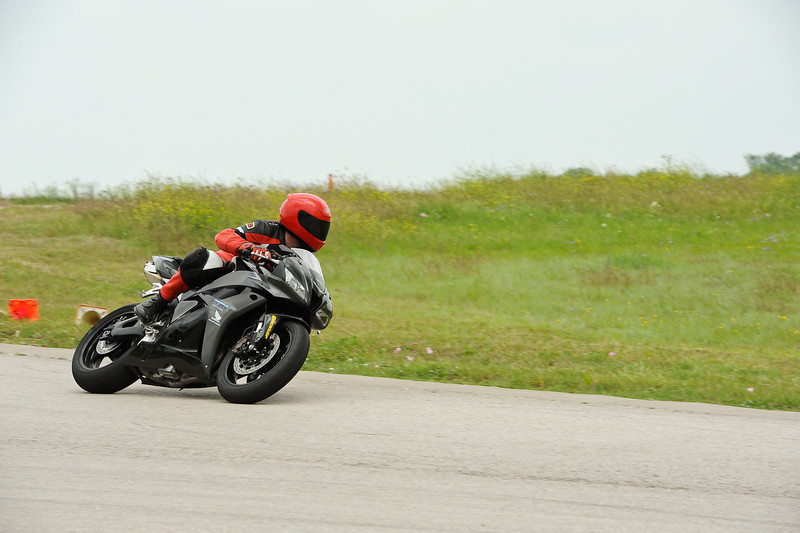 Black sport motorcycle with rider in red gear on a track