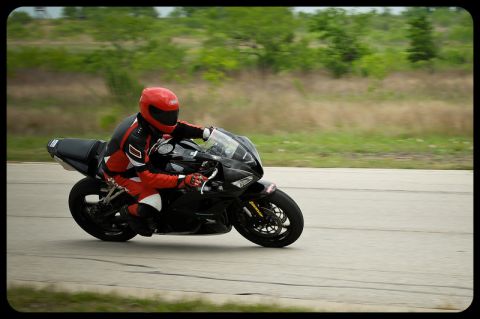 2001 Kawasaki KZ1000-A1 - A rider in full racing gear navigates a turn on a black sportbike during a track day.