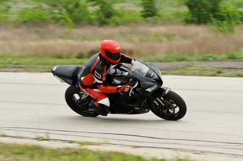 2001 Kawasaki KZ1000-A1 - A motorcyclist wearing a red helmet and racing suit navigates a turn on a closed course.
