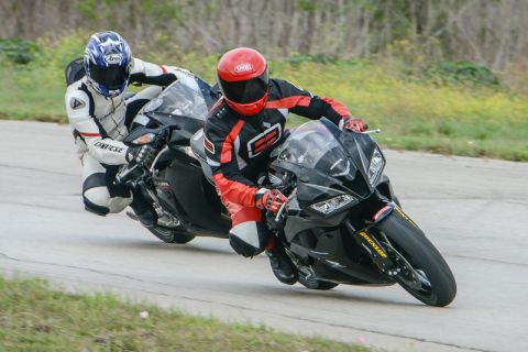 2001 Kawasaki KZ1000-A1 - Two sport motorcycles race on a track, leaning into a turn with riders in full racing gear.