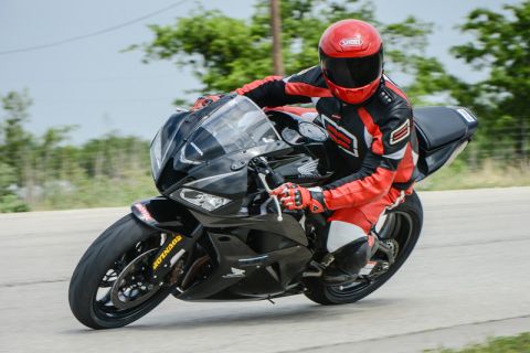 2001 Kawasaki KZ1000-A1 - A motorcycle rider in full racing gear takes a corner on a black sportbike.