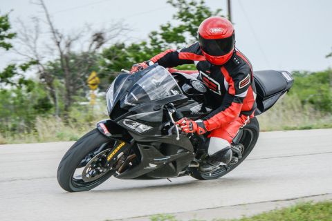 2001 Kawasaki KZ1000-A1 - A rider in full gear navigates a curve on a black sport motorcycle.