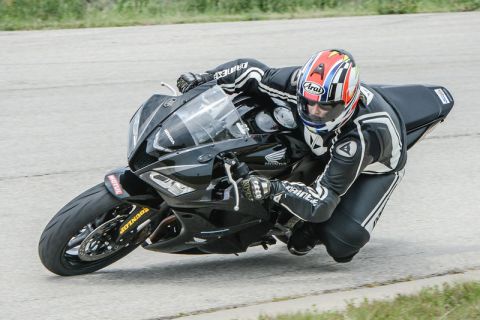 2001 Kawasaki KZ1000-A1 - A rider in full racing leathers leans a black Honda motorcycle into a turn on a track.