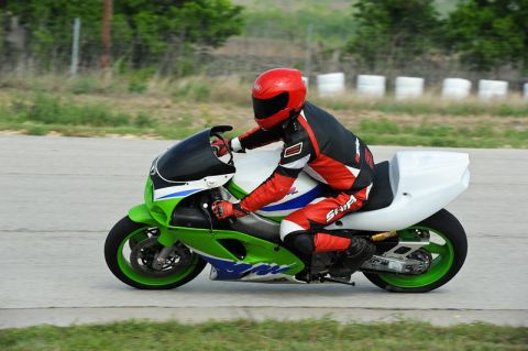 2001 Kawasaki KZ1000-A1 - A motorcycle rider in full gear speeds down a track on a green and white sportbike.