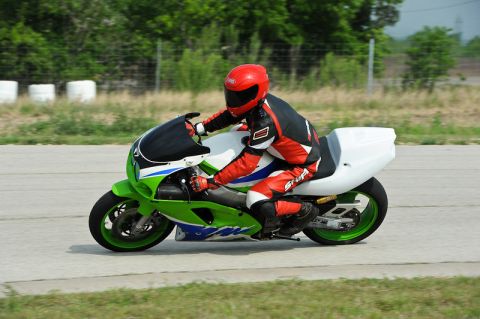 2001 Kawasaki KZ1000-A1 - A rider in full gear speeds down a track on a green and white sport motorcycle.