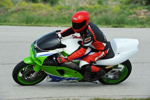 2001 Kawasaki KZ1000-A1 - A rider in racing gear speeds along a track on a green and white motorcycle.